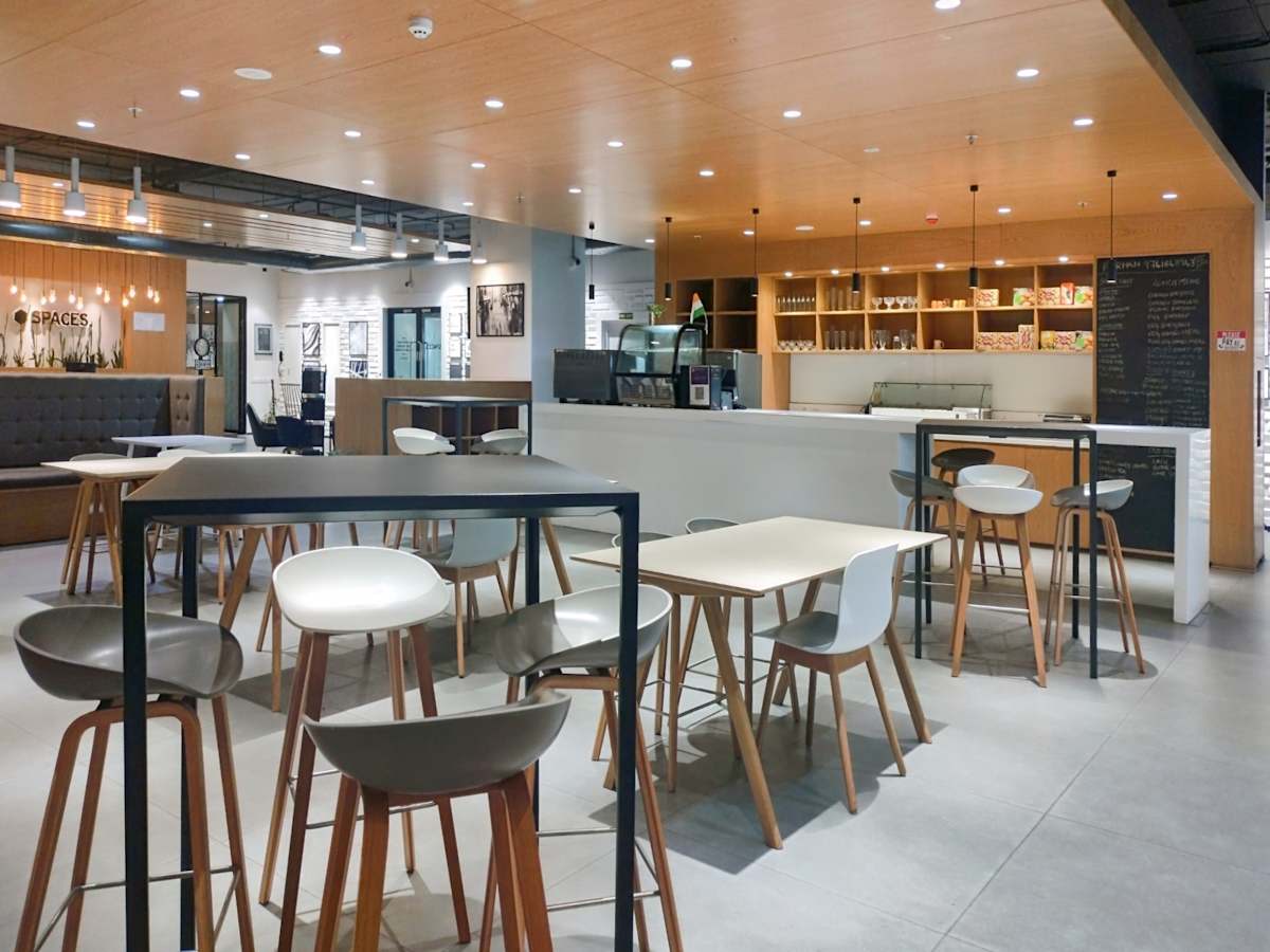 Modern coworking area with sleek high tables, ample seating, and a cozy café ambiance.