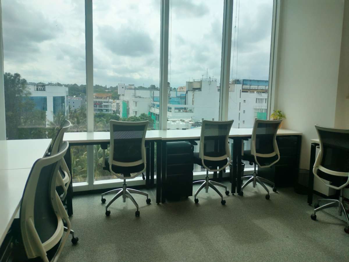 Bright coworking space with modern desks and ergonomic chairs, offering city views on Embassy Golf Links Road.