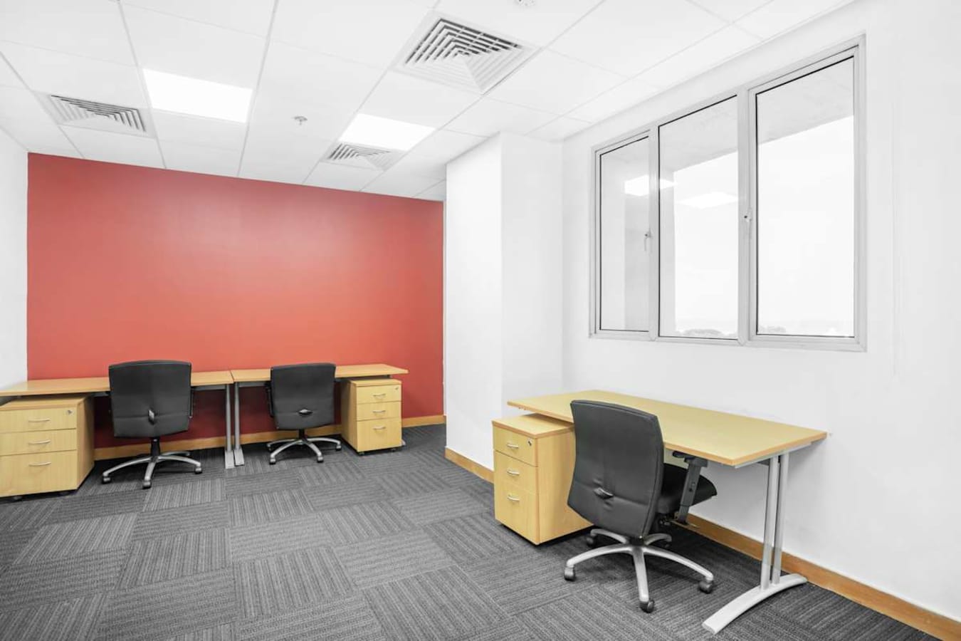 Bright coworking space with modern desks, ergonomic chairs, and a vibrant accent wall.