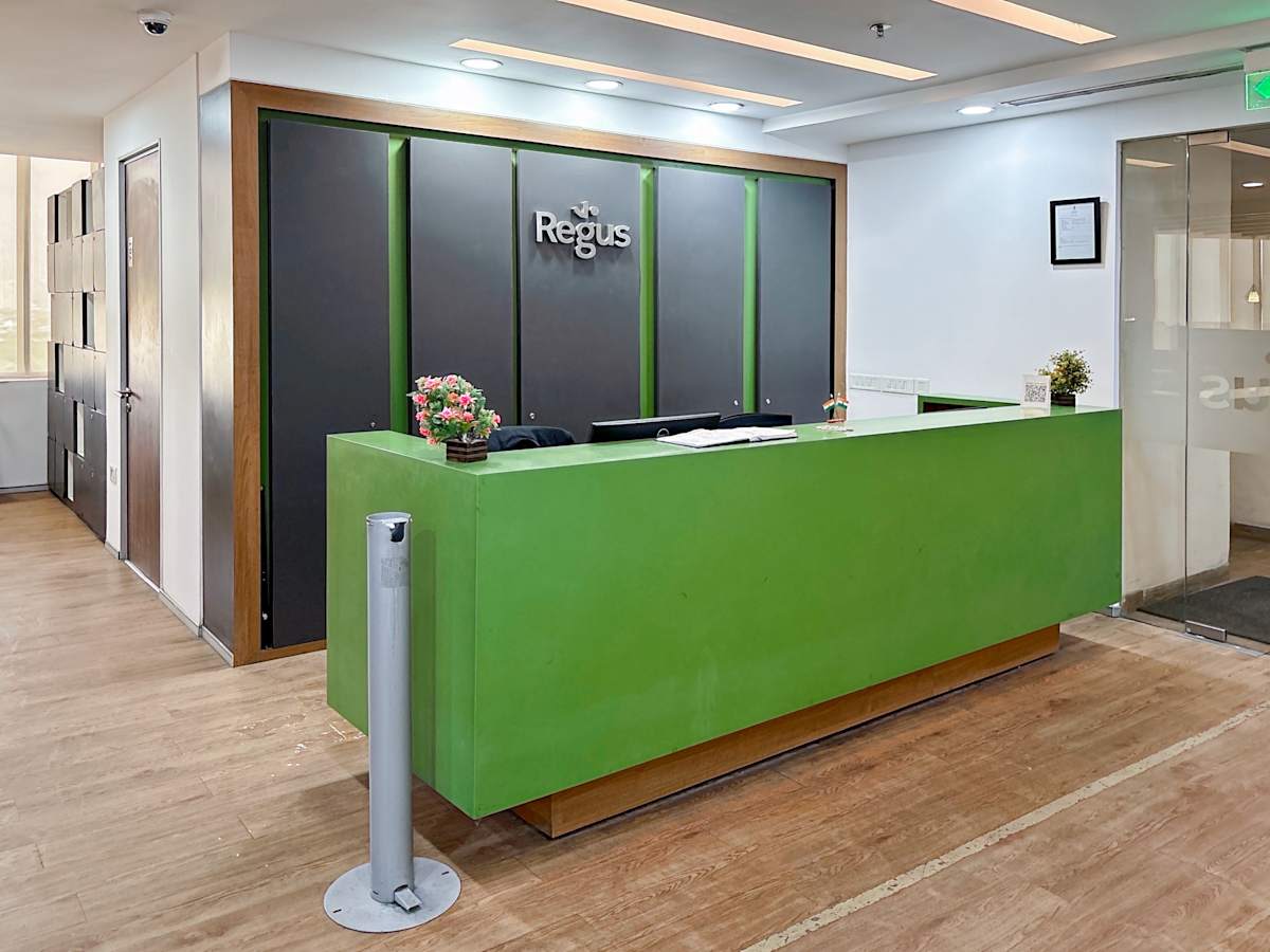 Modern coworking reception with bright green desk and sleek wood accents in Sale Shop location.