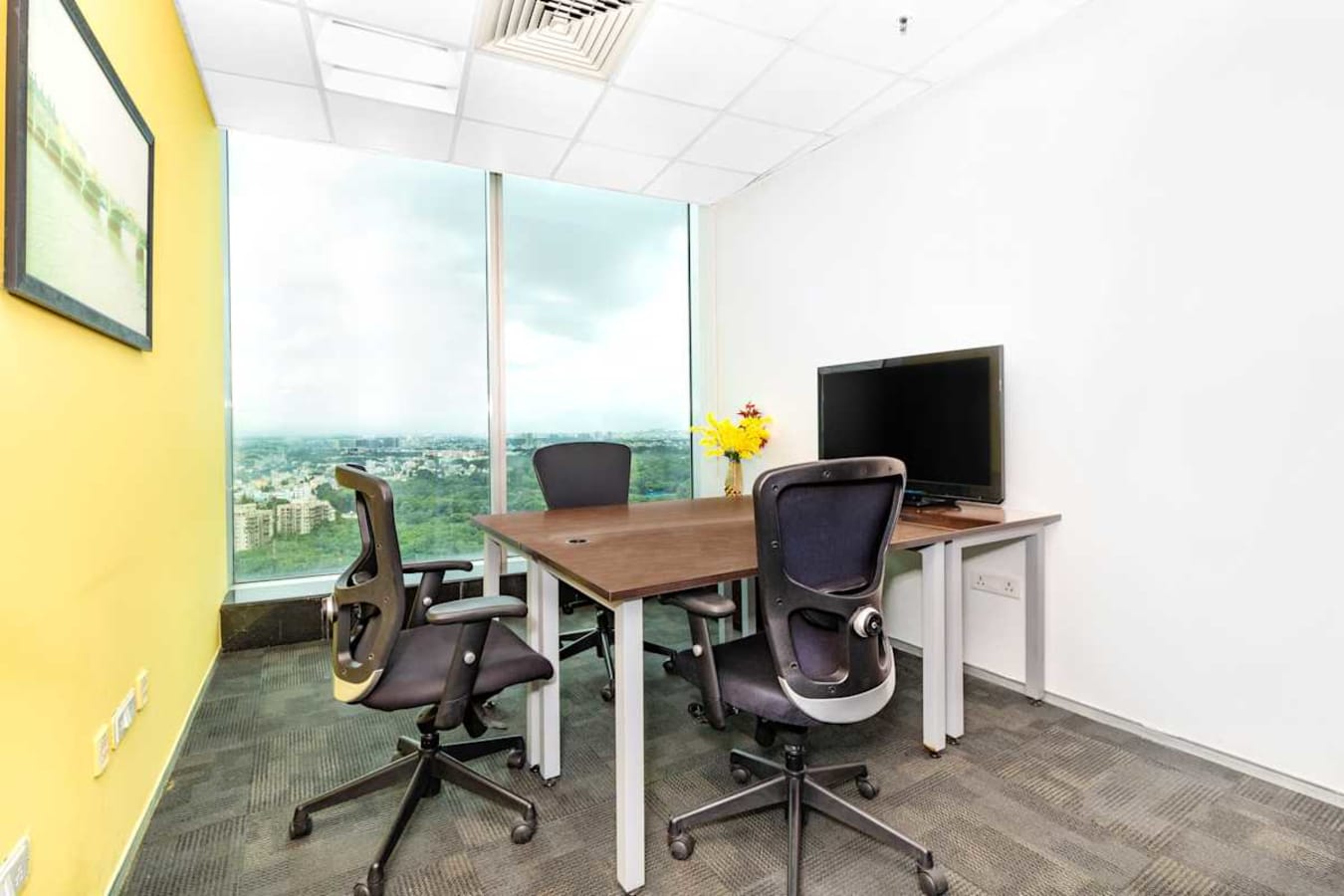 Bright coworking space with a view, featuring ergonomic chairs and a sleek desk setup.