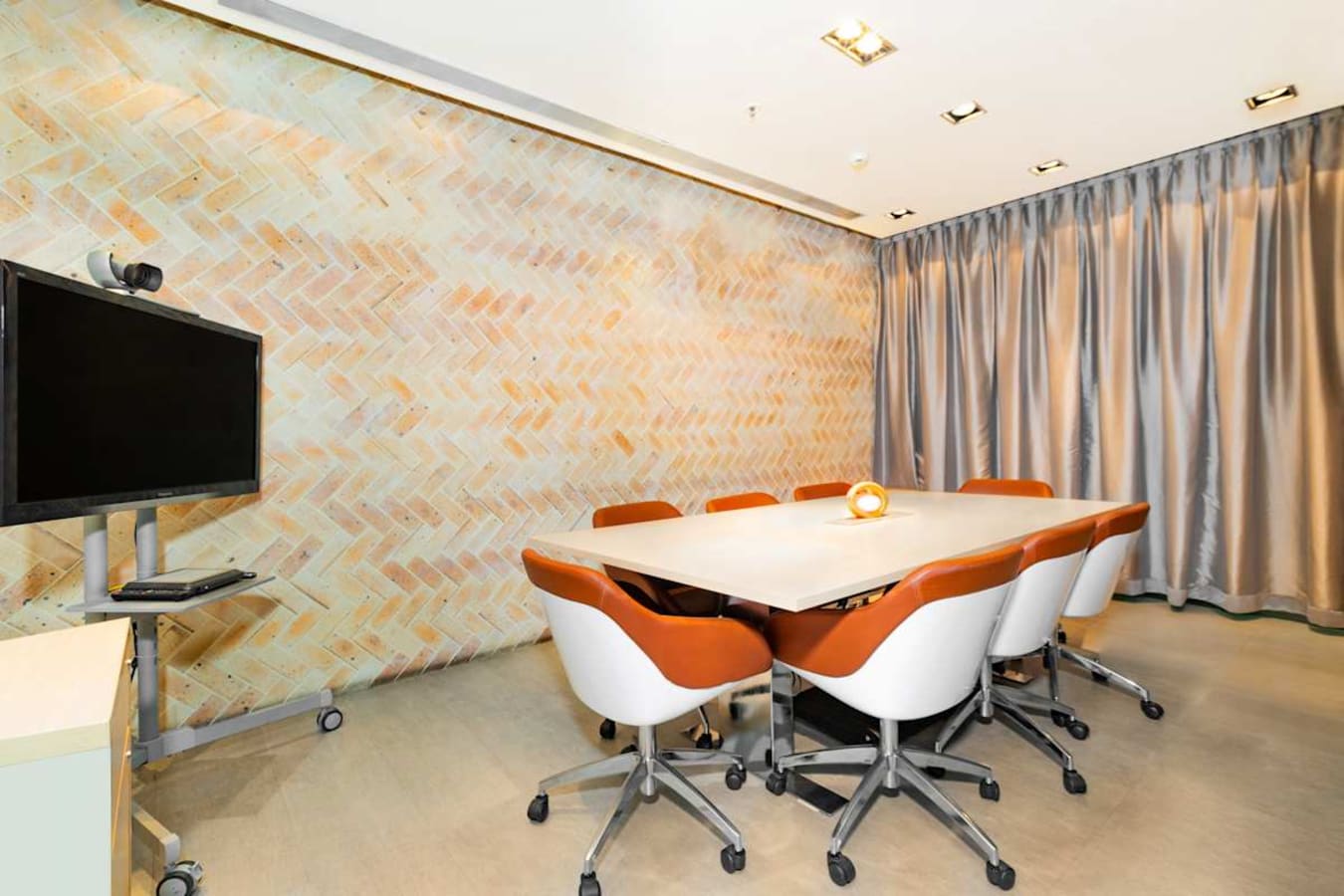 Modern meeting room with stylish chairs, brick accent wall, and privacy curtains.