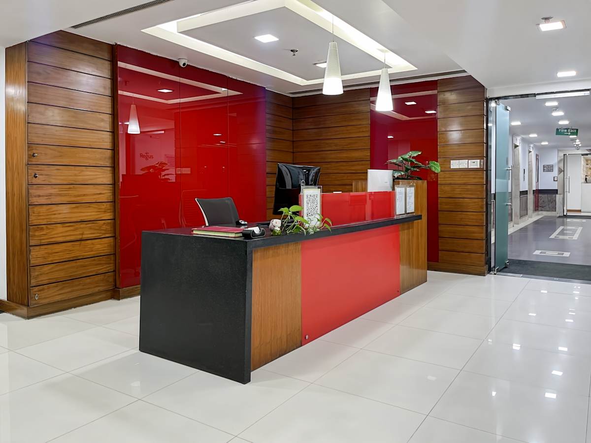 Modern coworking space with sleek reception, vibrant red accents, and ample natural light.