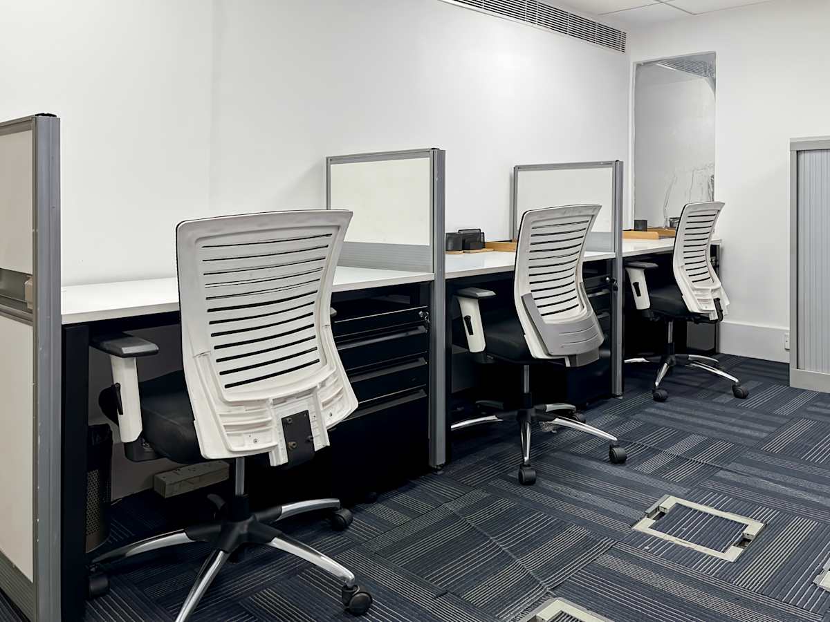 Modern coworking desks with ergonomic chairs and ample lighting on Mehrauli-Gurgaon Road.