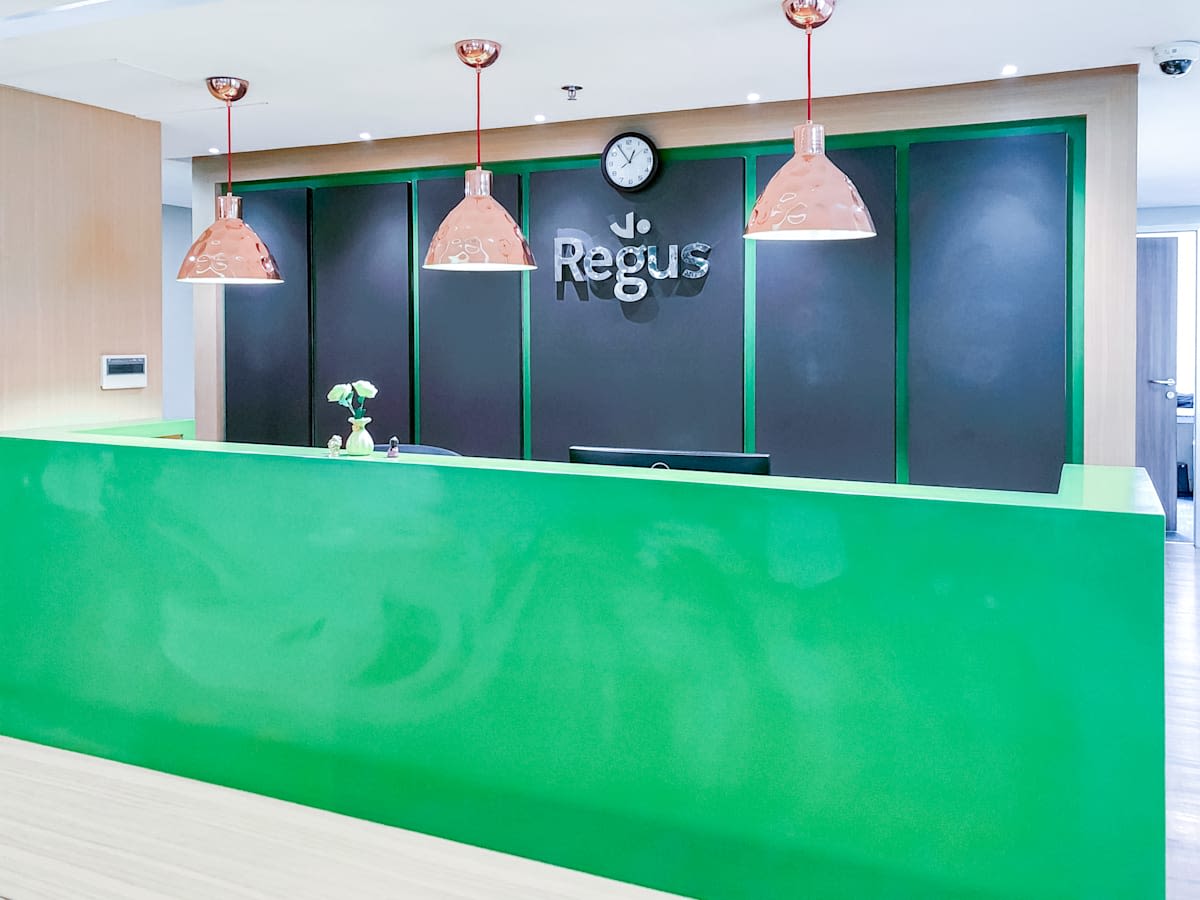 Bright, modern reception area with vibrant green desk and stylish pendant lighting.