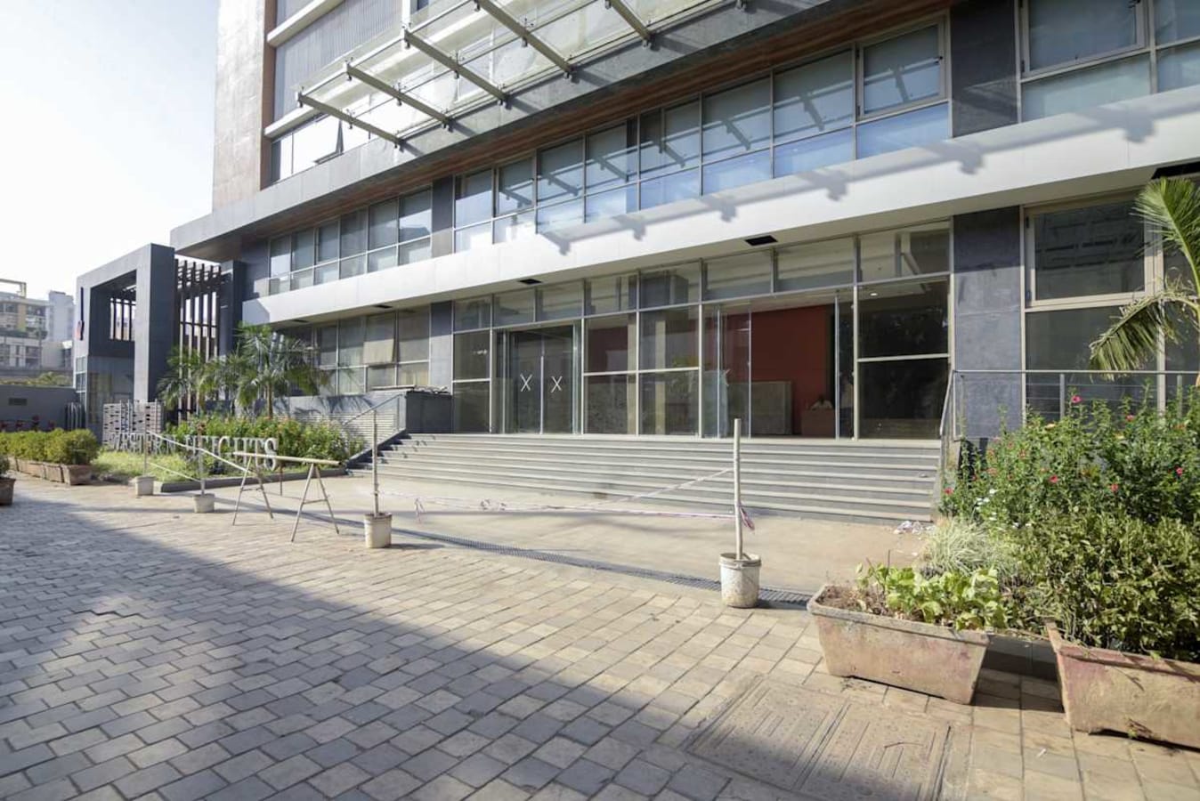 Modern coworking space entrance with sleek glass facade and welcoming outdoor area.