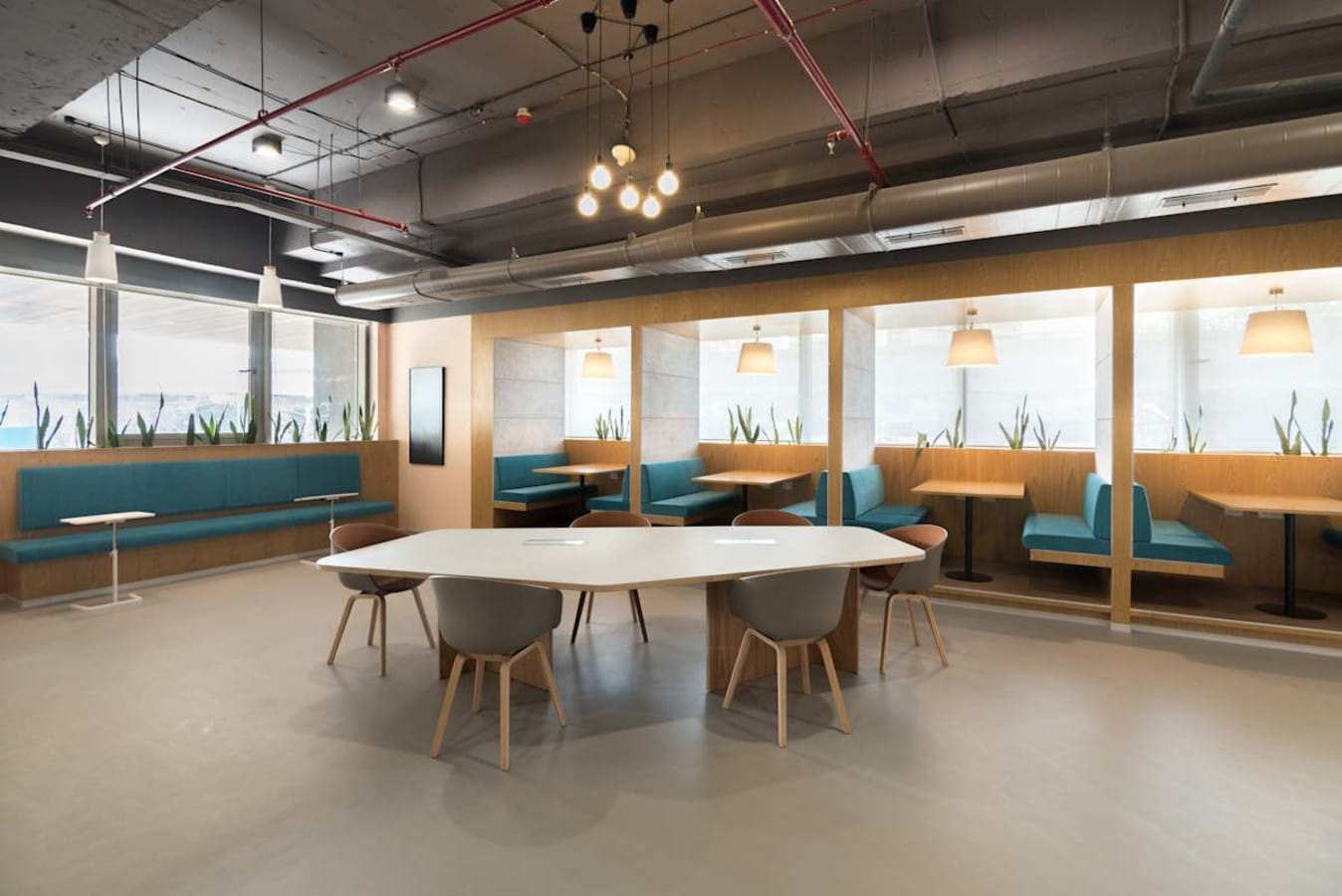 Modern coworking space with cozy booths, ample natural light, and sleek furnishings.