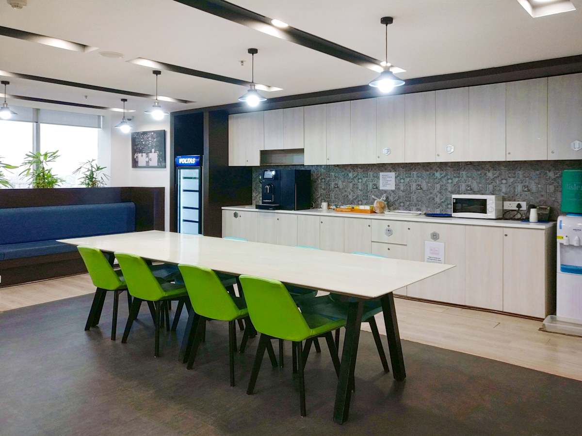 Modern coworking space with a bright kitchen area and communal dining table in Gurugram.