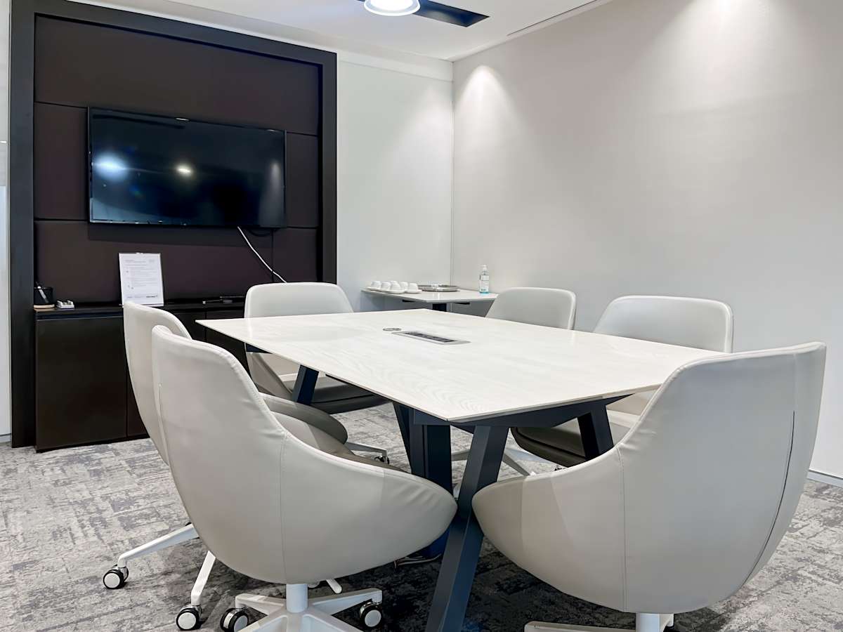 Modern meeting room with sleek chairs, a large table, and a wall-mounted screen. Ideal for collaboration.