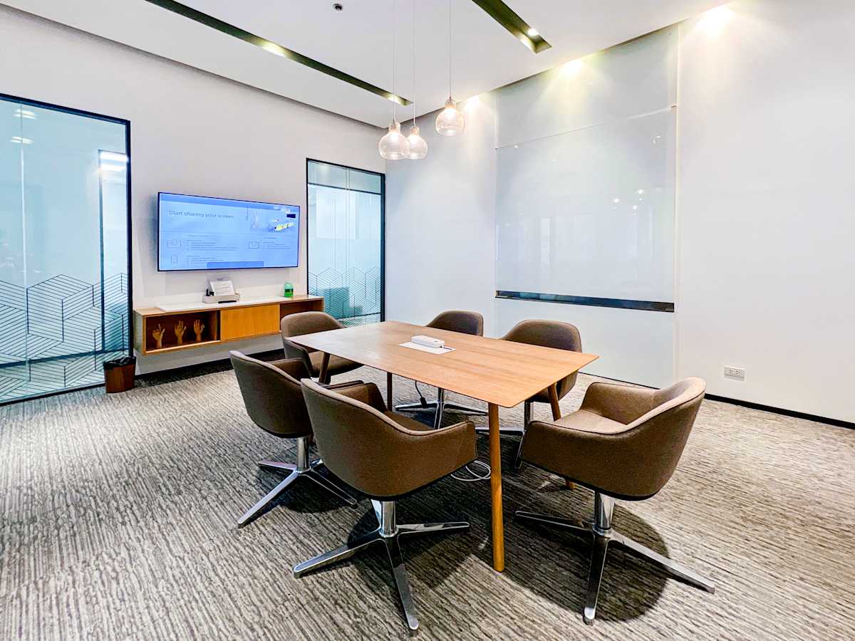 Modern coworking space with sleek conference area, ample lighting, and AV setup. Ideal for meetings.