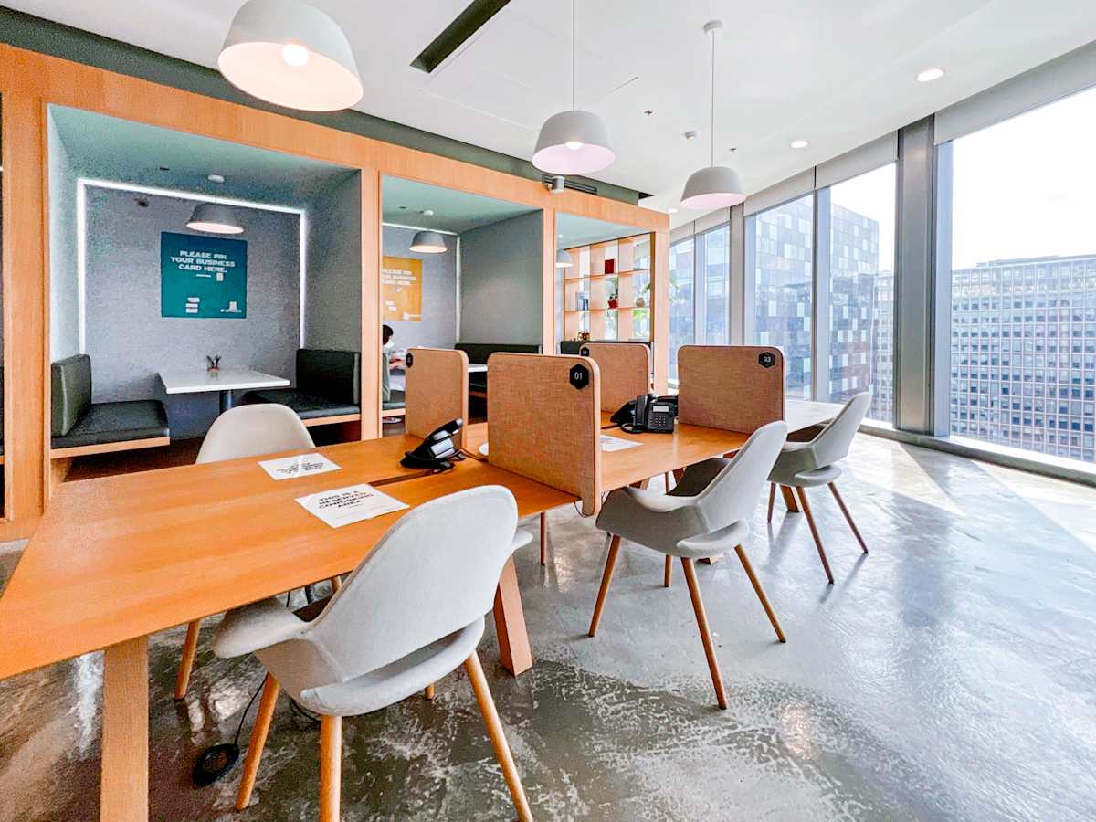 Modern coworking space with open desks and cozy pods, featuring stunning city views.