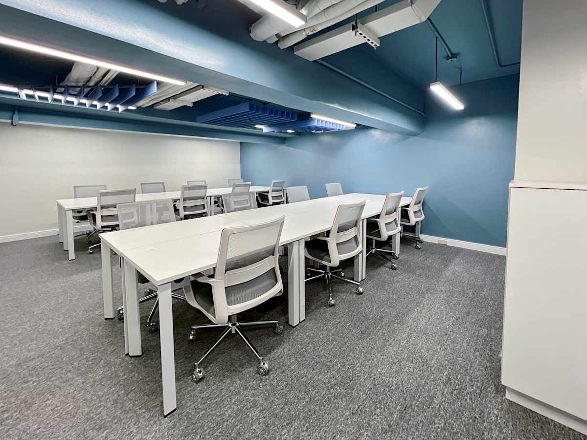 Modern coworking space with ample seating, sleek white desks, and vibrant blue accents.