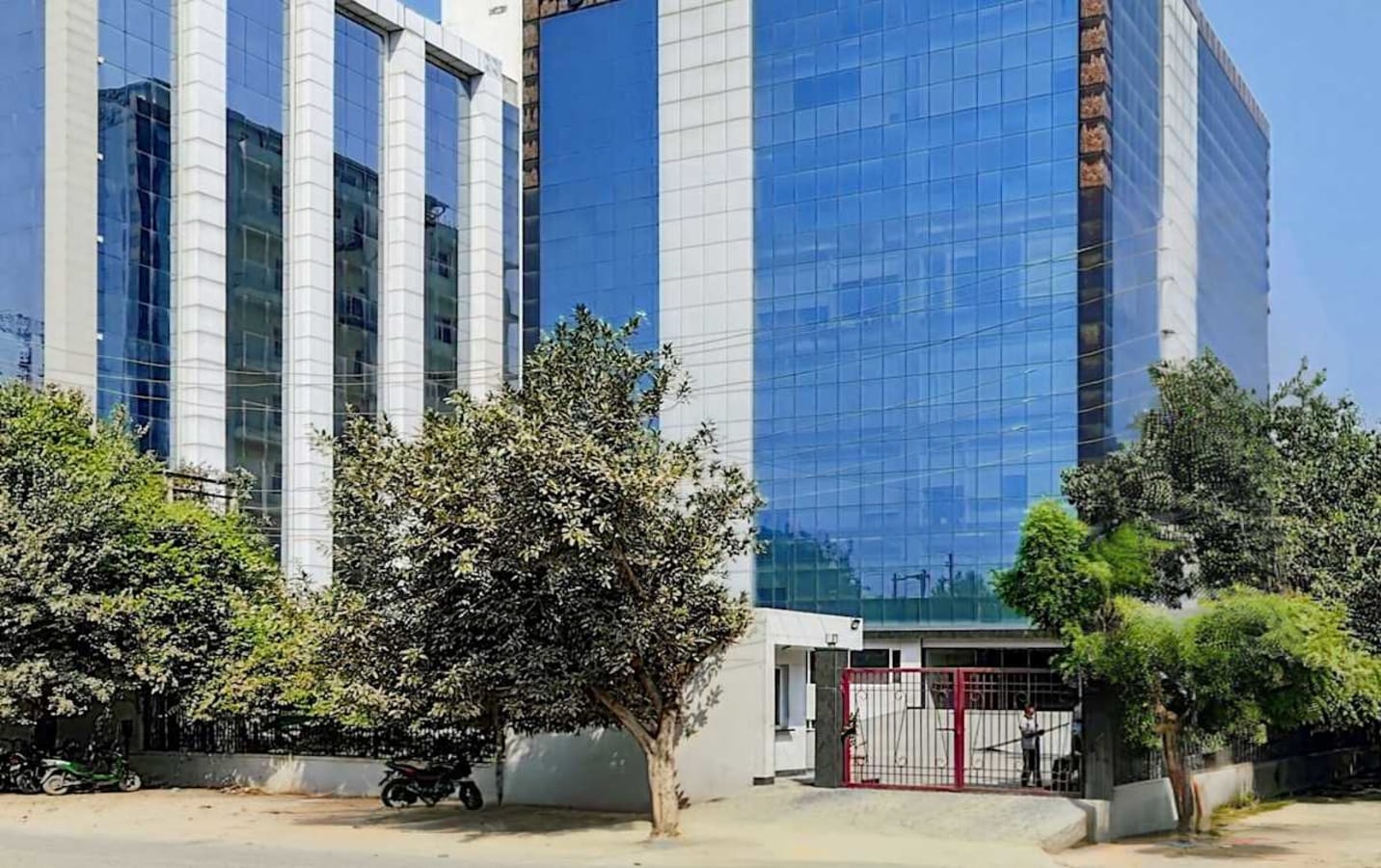 Modern coworking space in Noida featuring sleek glass facade and lush greenery.