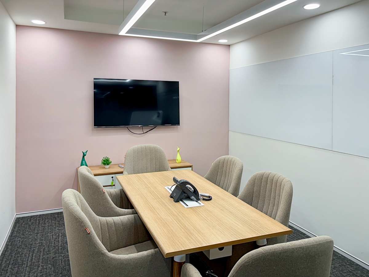 Modern meeting room with a sleek table, comfortable chairs, and smart TV, ideal for collaboration.