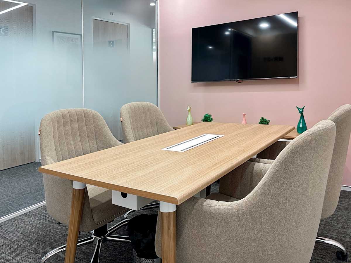 Modern Noida coworking space with sleek meeting room, stylish chairs, and smart TV.