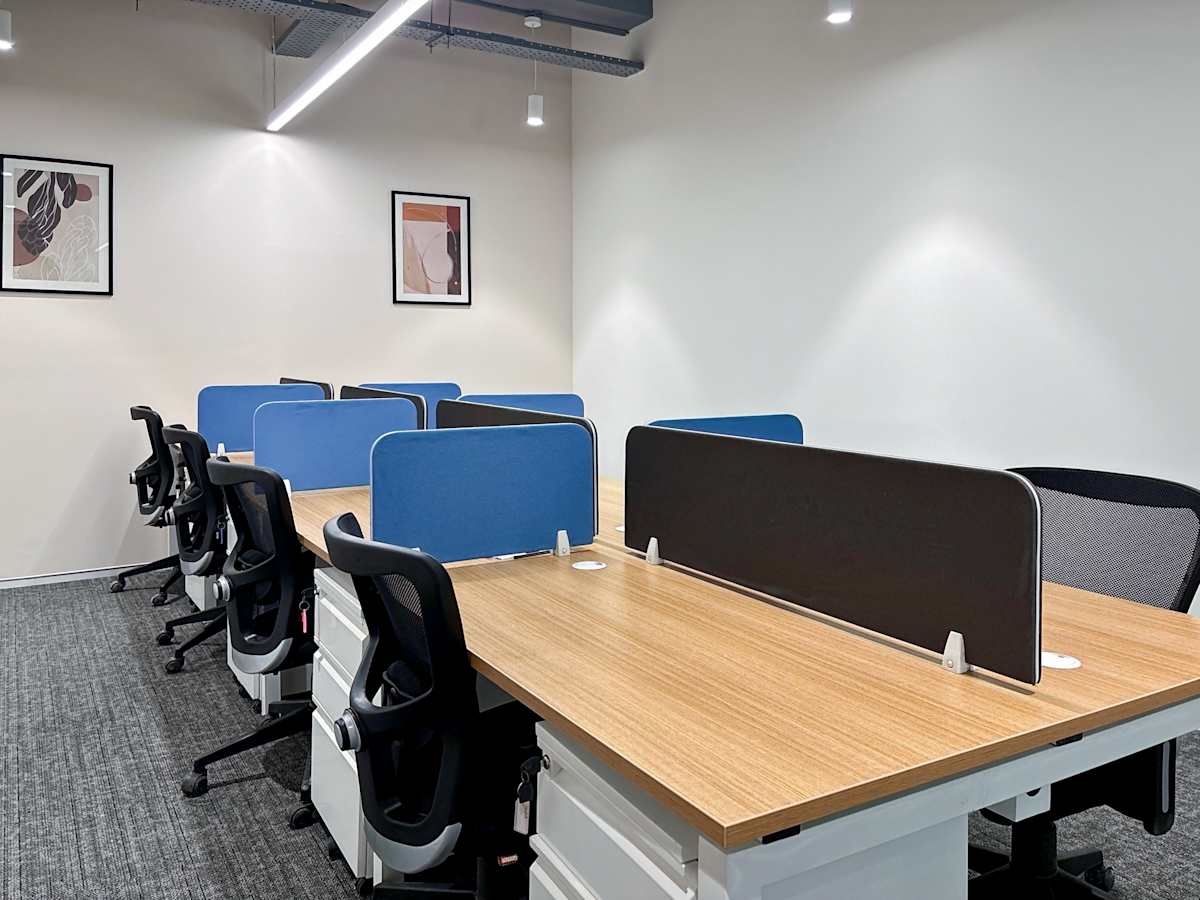 Modern coworking space in Noida featuring spacious desks, ergonomic chairs, and bright lighting.