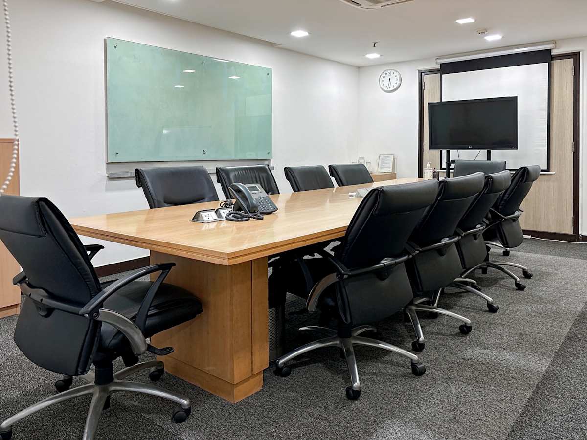 Modern conference room with a large table, ergonomic chairs, and a presentation screen. Ideal for meetings.