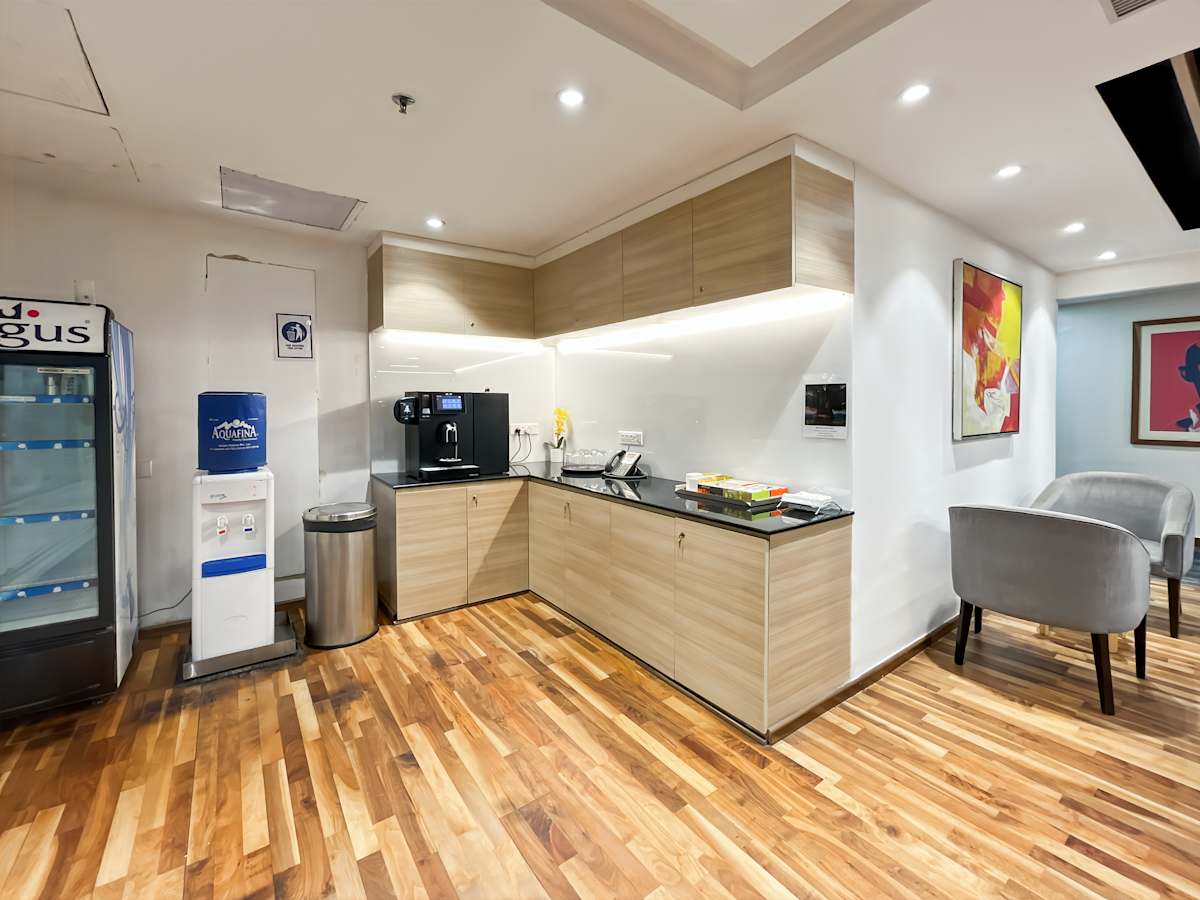 Modern coworking kitchen with sleek wood flooring, coffee machine, and vibrant artwork.