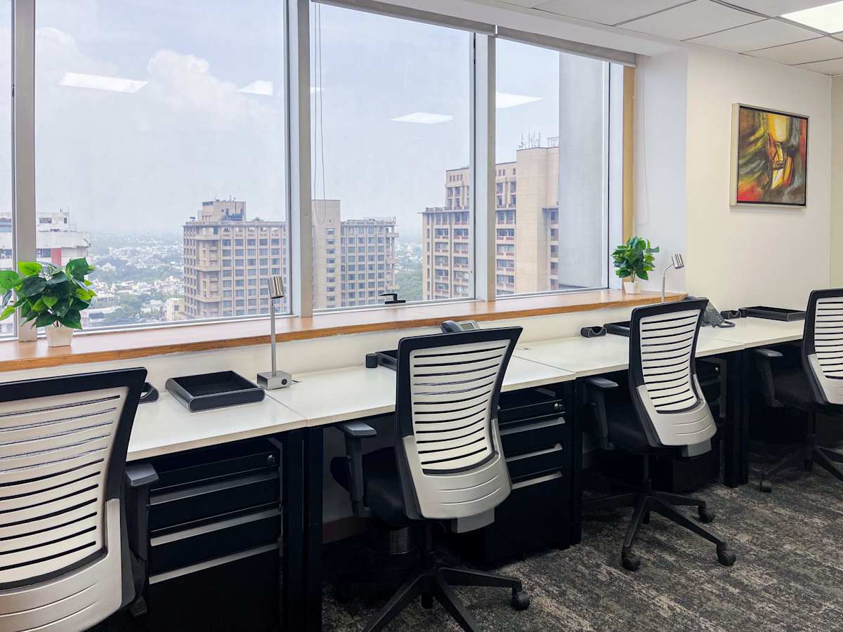 Modern coworking space with city views, ergonomic chairs, and natural light.