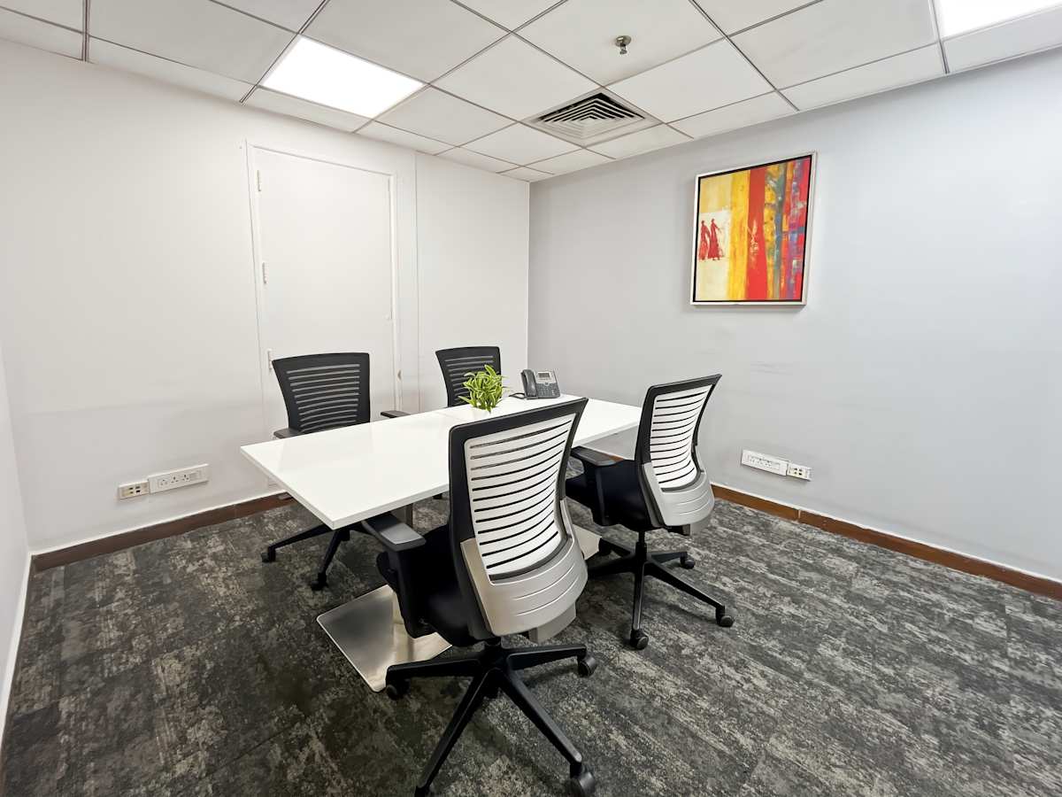 Modern meeting room with sleek furniture, vibrant art, and ample lighting. Perfect for collaboration.