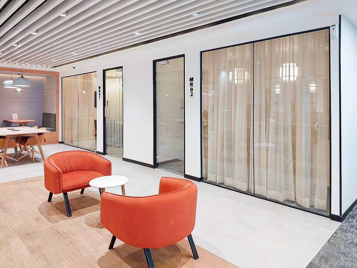 Modern coworking space with vibrant seating, glass-walled meeting rooms, and stylish decor in मुंबई.