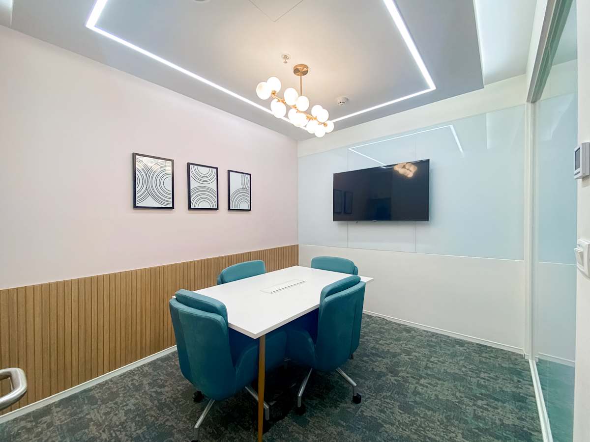 Sleek meeting room with modern decor, plush seating, and a wall-mounted screen. Perfect for collaboration.