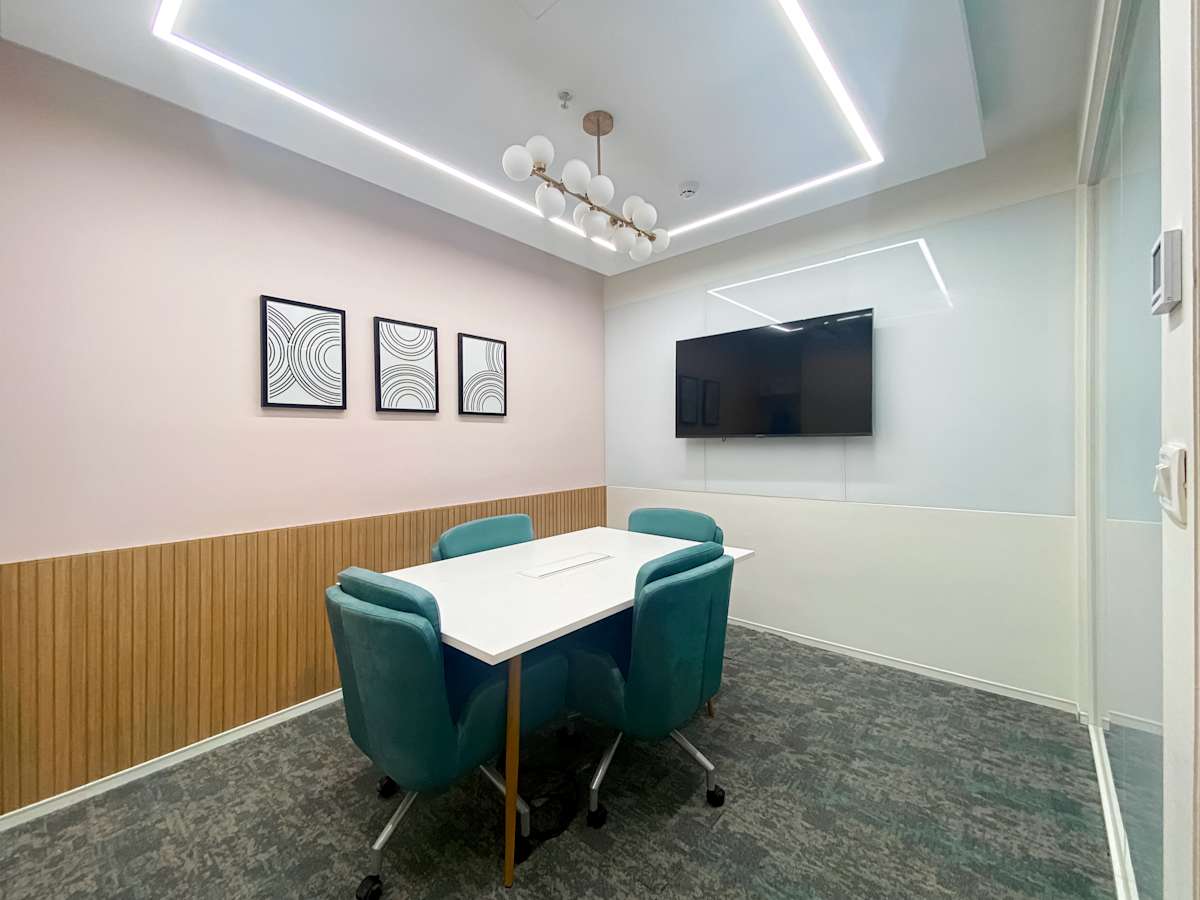 Modern meeting room with a sleek table, plush chairs, and smart TV. Ideal for collaboration.