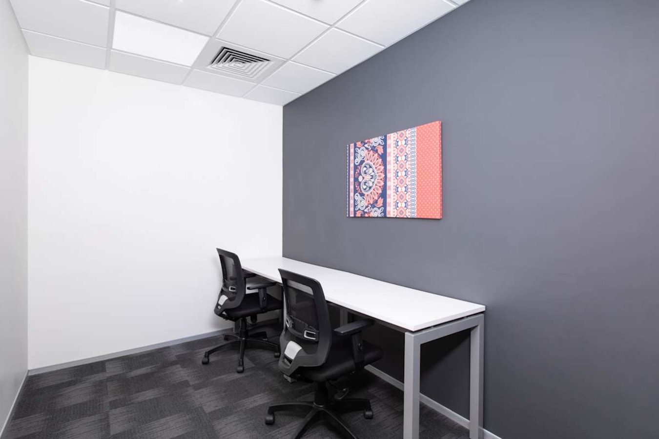 Sleek private office with modern furnishings and vibrant wall art for focused work sessions.