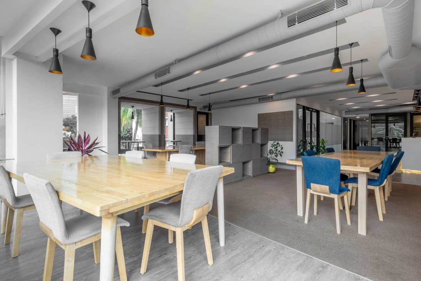 Modern coworking area with ample natural light, stylish seating, and collaborative tables.