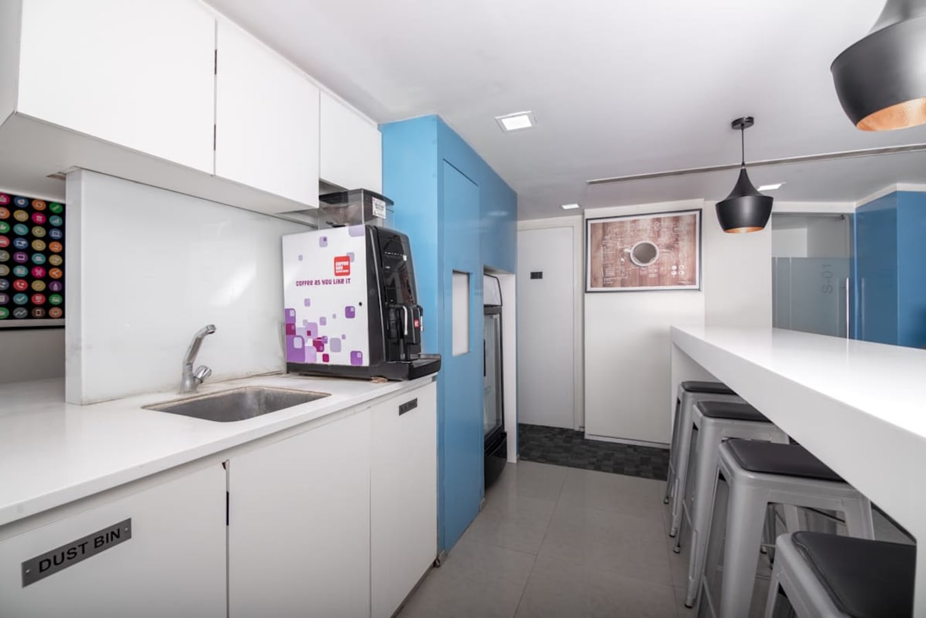 Modern coworking kitchen with sleek design, coffee machine, and ample seating on Sion-Trombay Road.