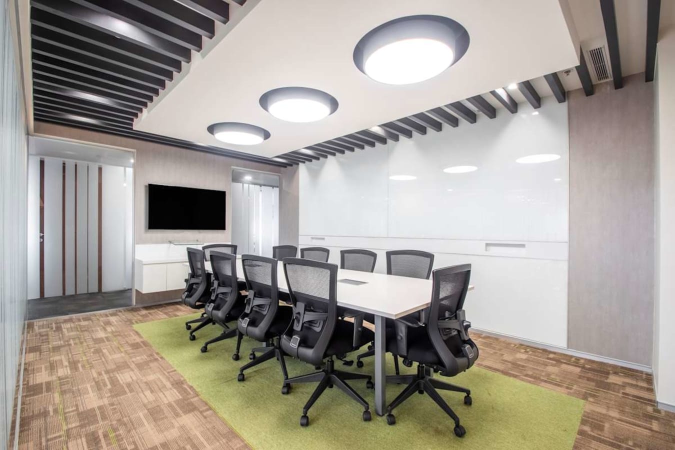 Modern meeting room with a sleek conference table, ergonomic chairs, and smart TV setup. Perfect for collaborative sessions.
