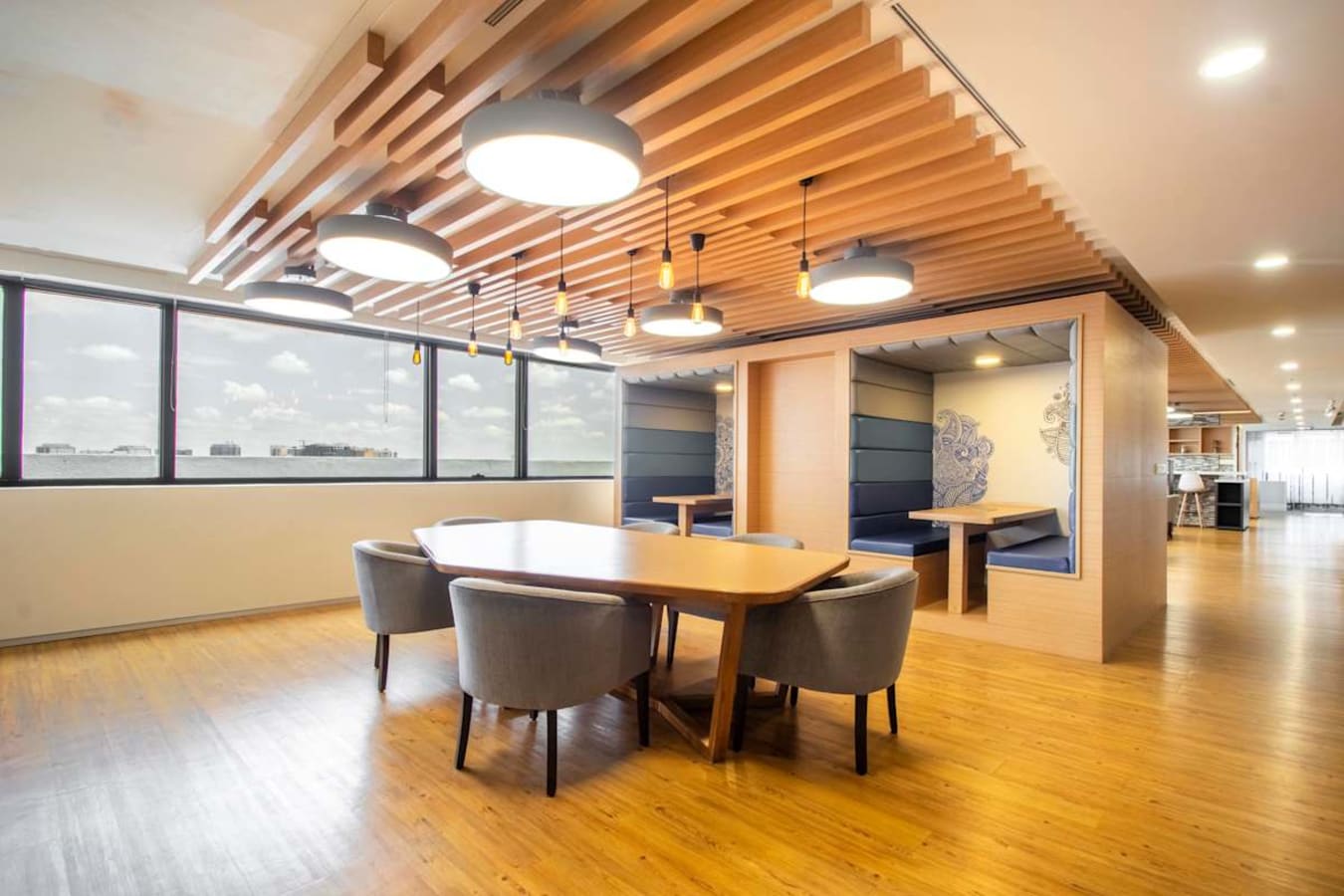 Modern coworking space with ample natural light, vibrant seating, and stylish wooden accents.