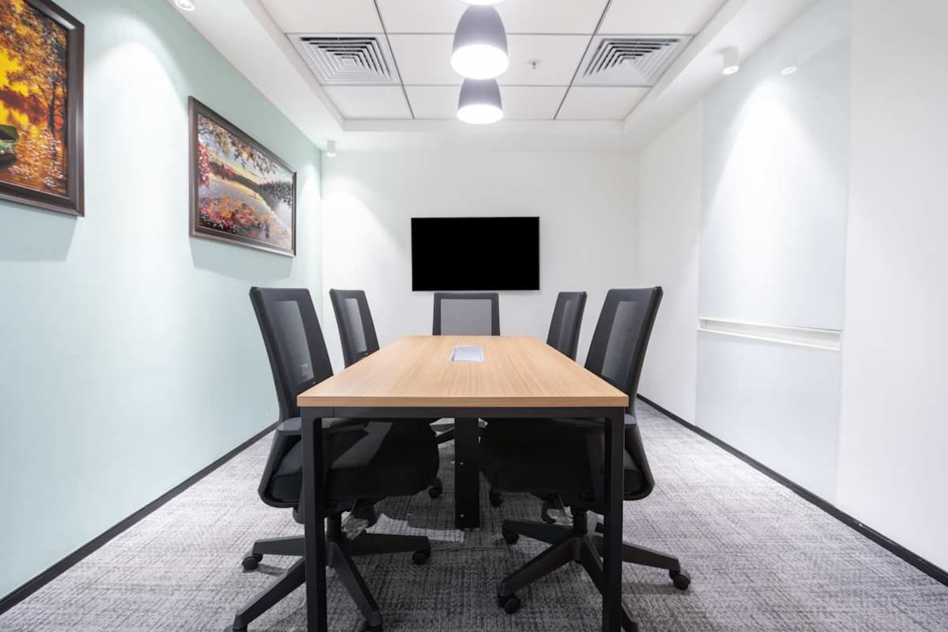 Modern meeting room with sleek design, optimal lighting, and seating for six in Delhi's Phase 1.
