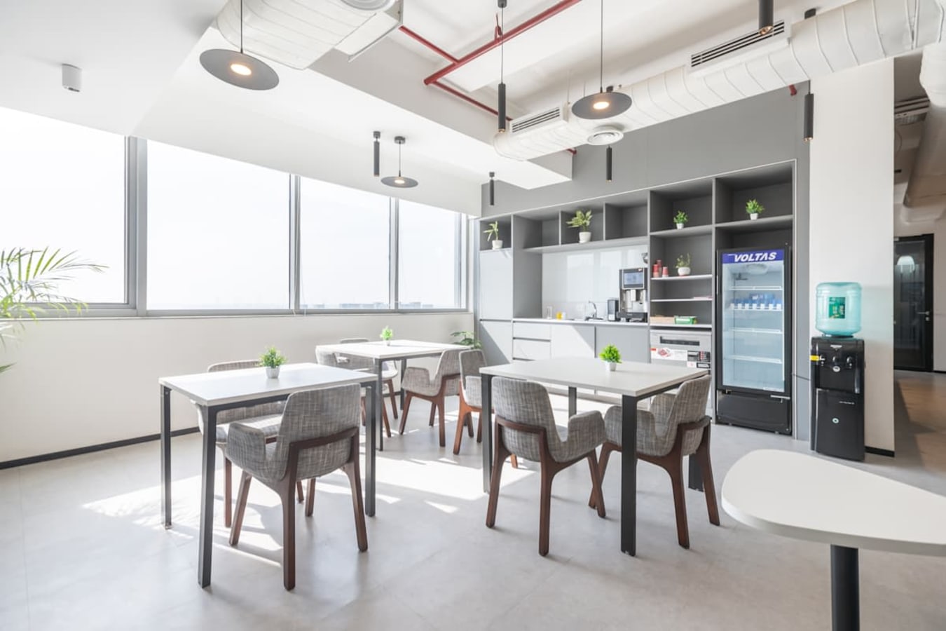 Bright coworking space with modern furnishings, ample natural light, and a convenient kitchenette.