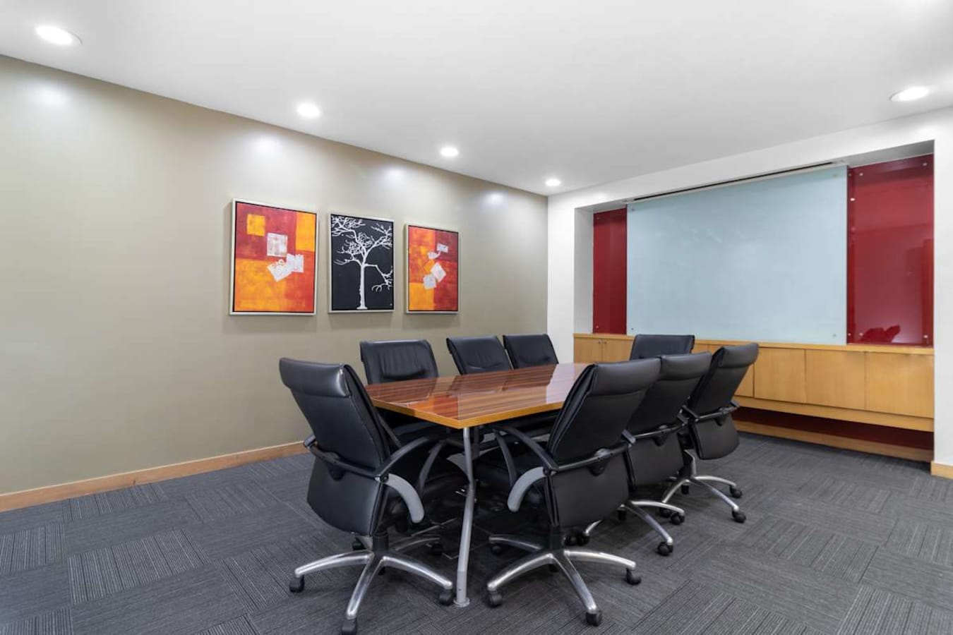 Modern conference room with sleek table, ergonomic chairs, and vibrant wall art. Ideal for meetings.
