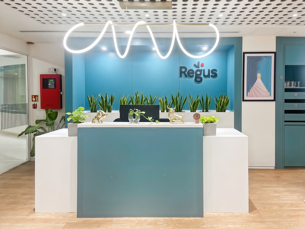 Stylish reception with vibrant decor and lush greenery at a flexible coworking space.