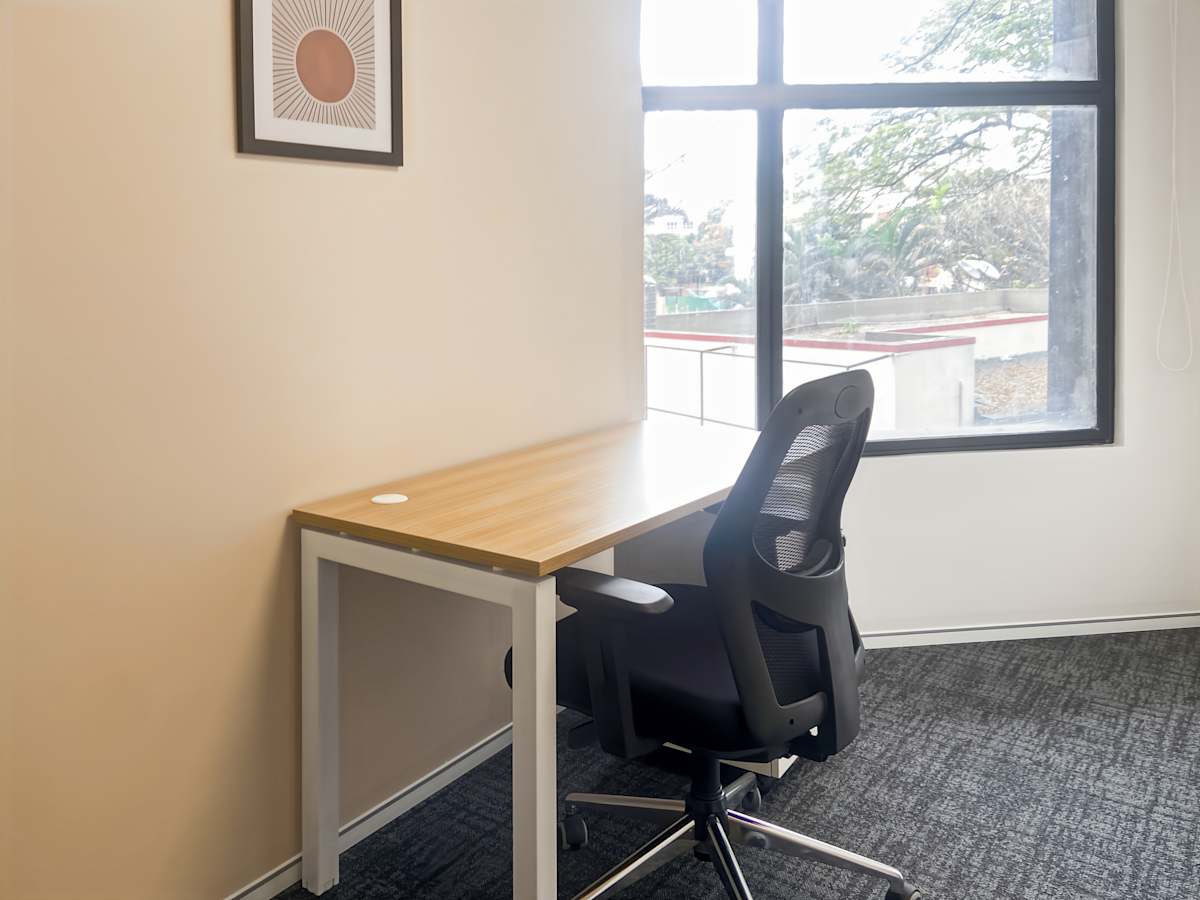 Bright, minimalist workspace with ergonomic chair and window view in Karnataka coworking space.