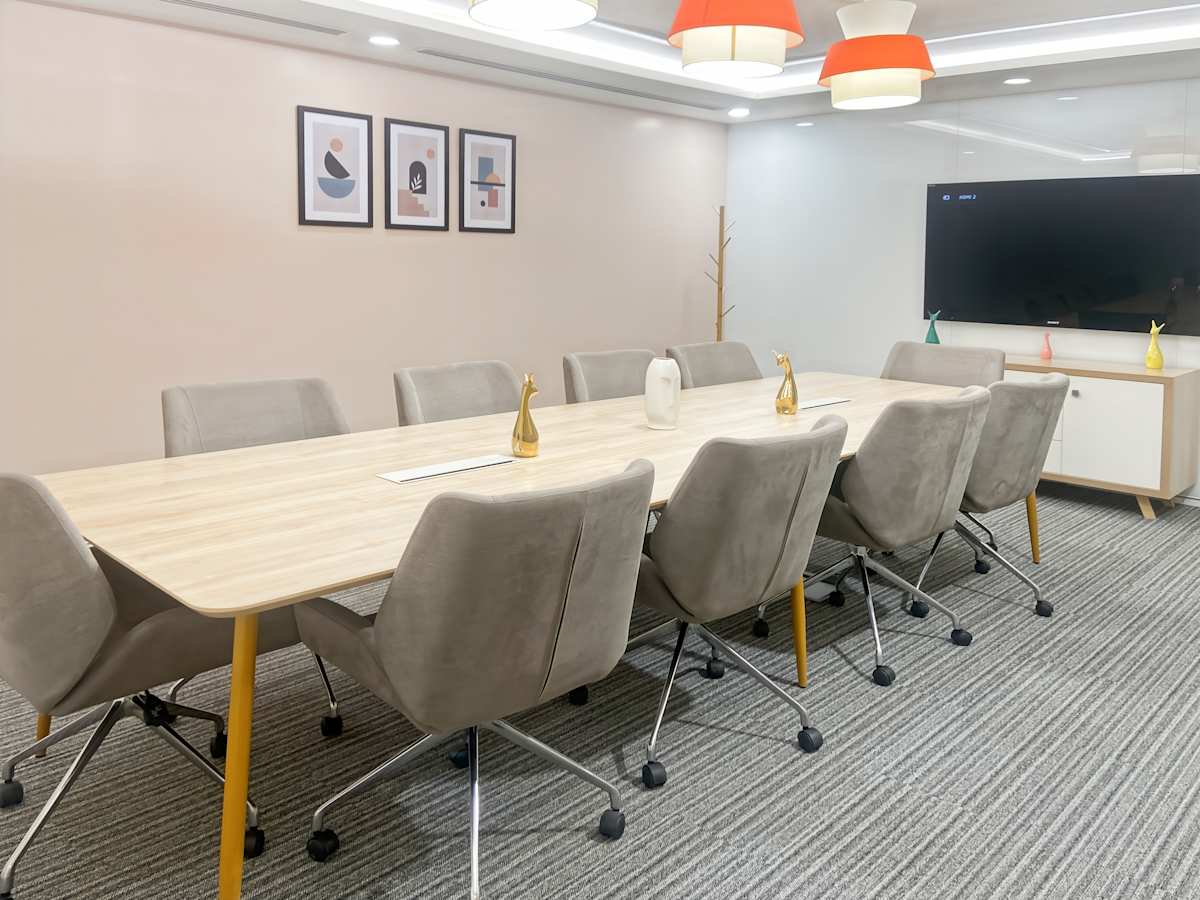 Modern conference room with ergonomic chairs, large meeting table, and bright, stylish lighting.
