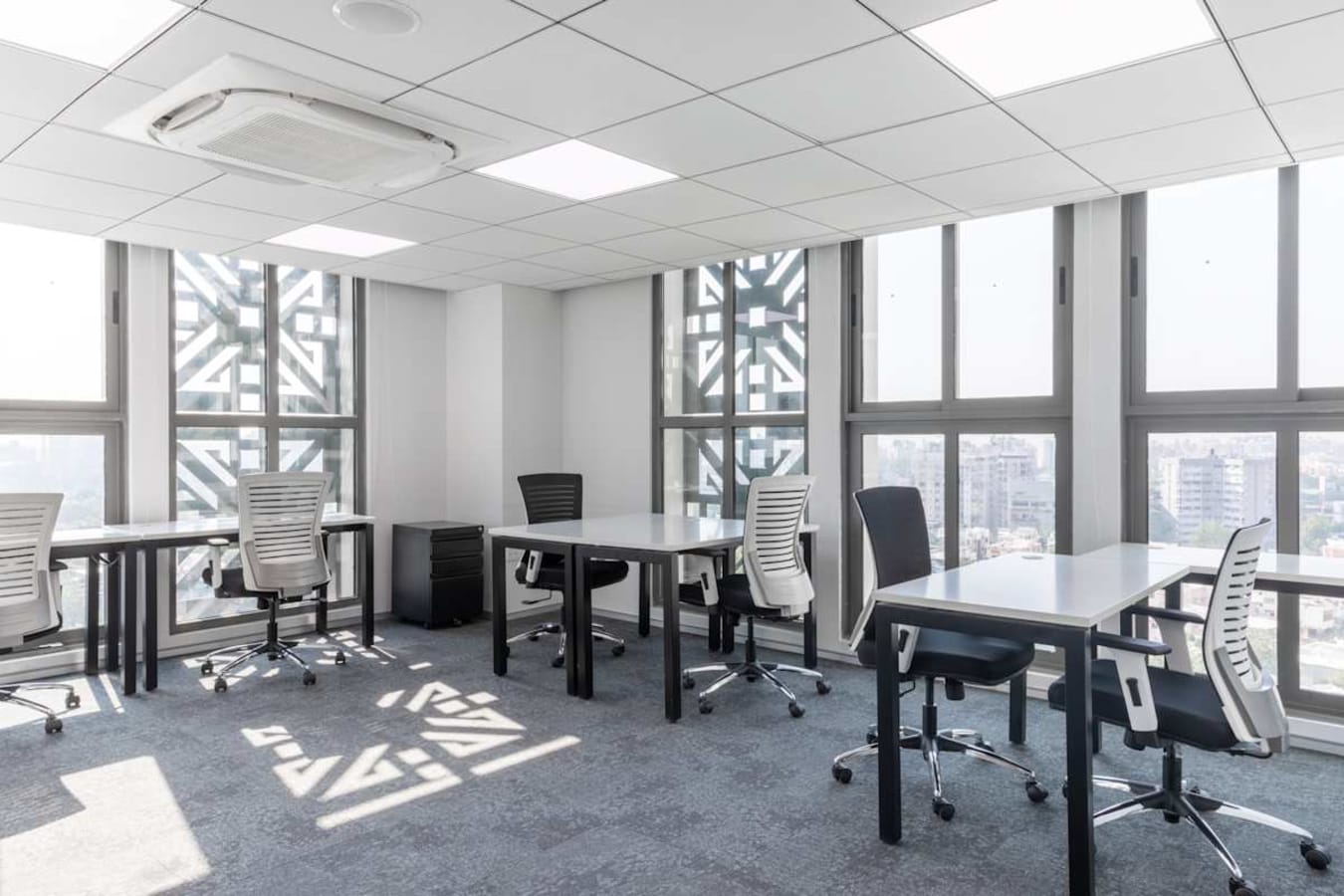 Bright coworking space with modern desks and ergonomic chairs, offering city views and ample natural light.