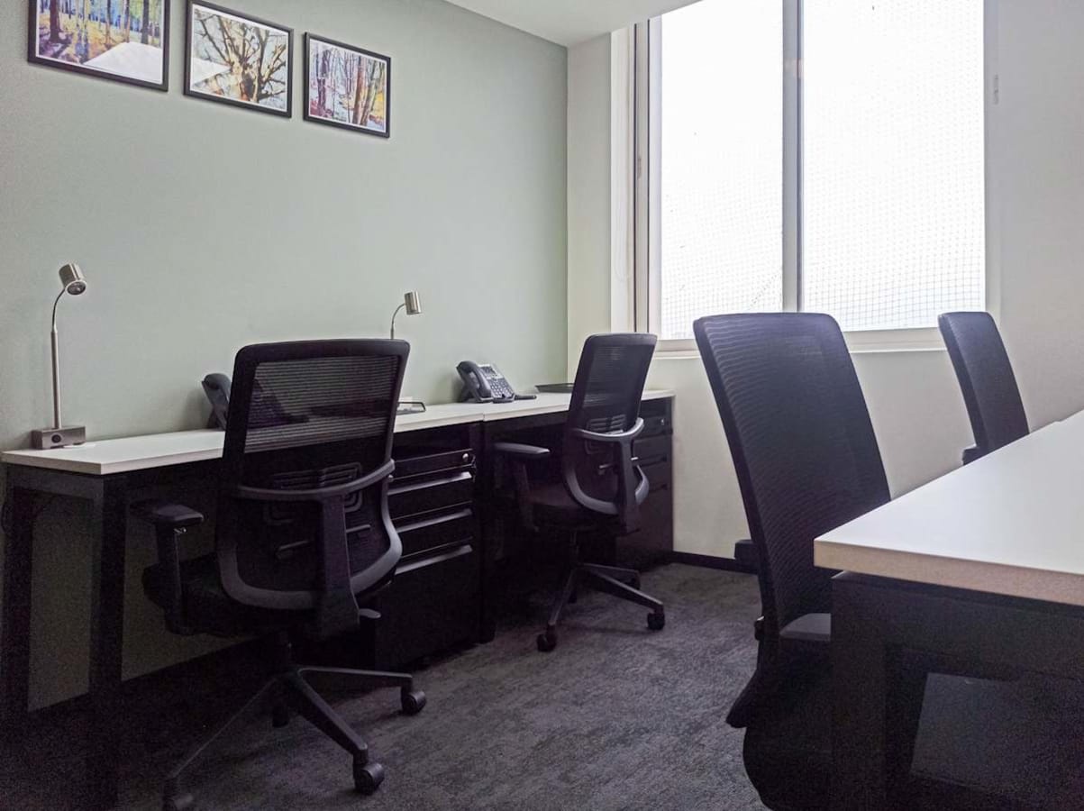 Modern coworking space with ergonomic chairs, ample natural light, and sleek workstations.