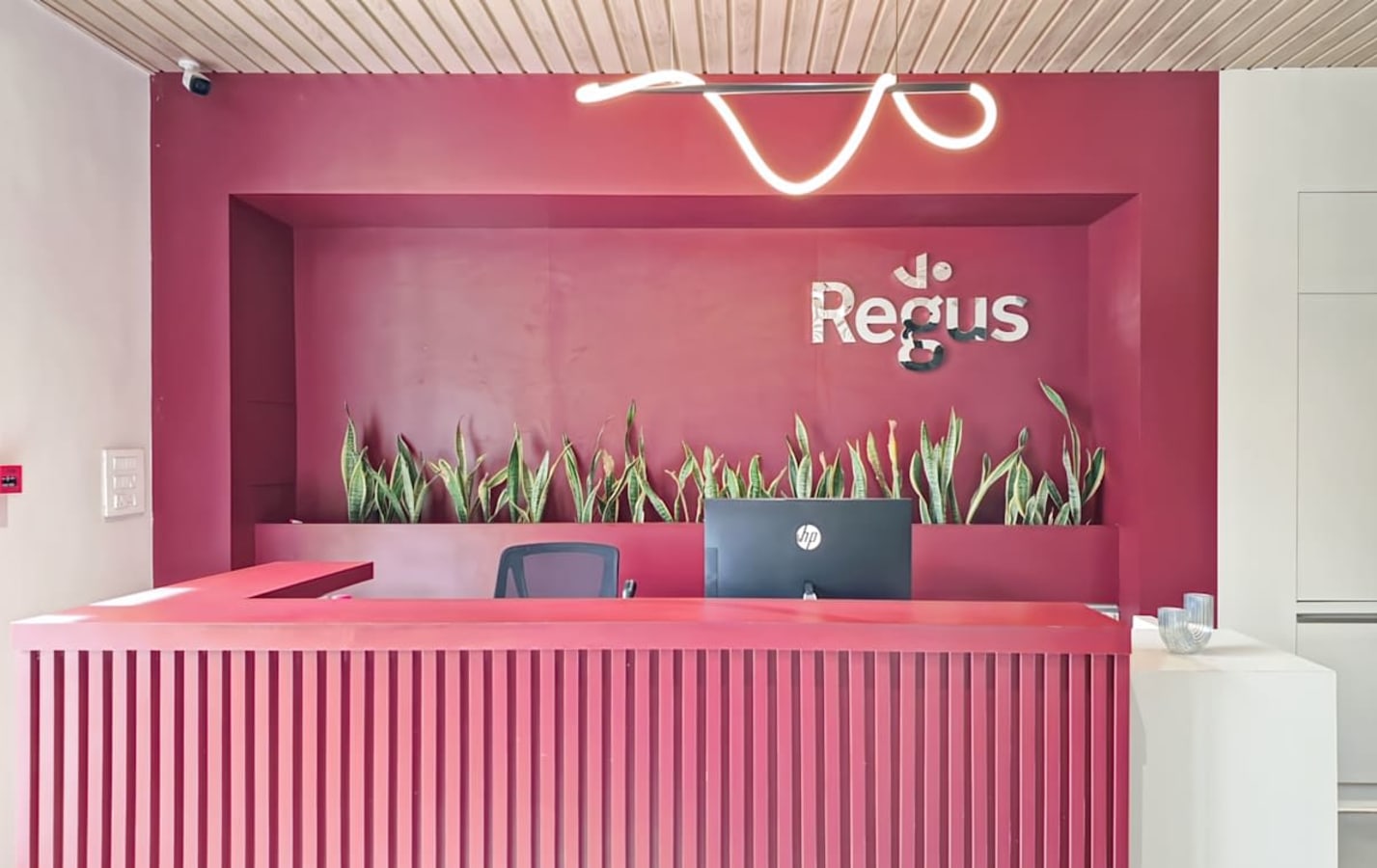 Modern reception area with vibrant red design, sleek desk, and greenery accents.