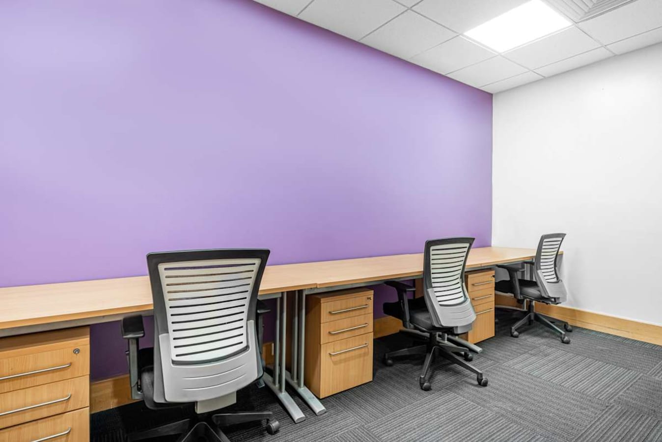 Modern coworking space with ergonomic chairs and vibrant purple accent wall. Ideal for productivity.