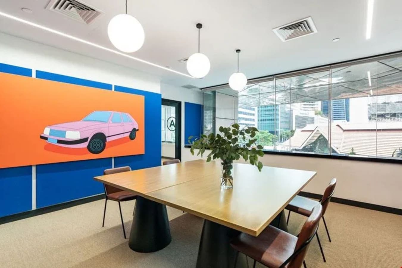 Modern meeting room with natural light, stylish décor, and seating for collaborative work.