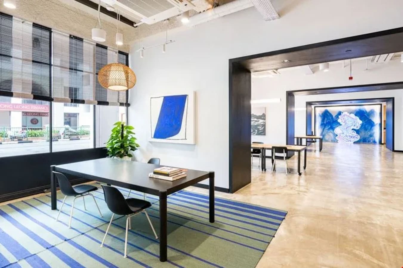 Bright, modern coworking space with open layout, vibrant artwork, and ample natural light.