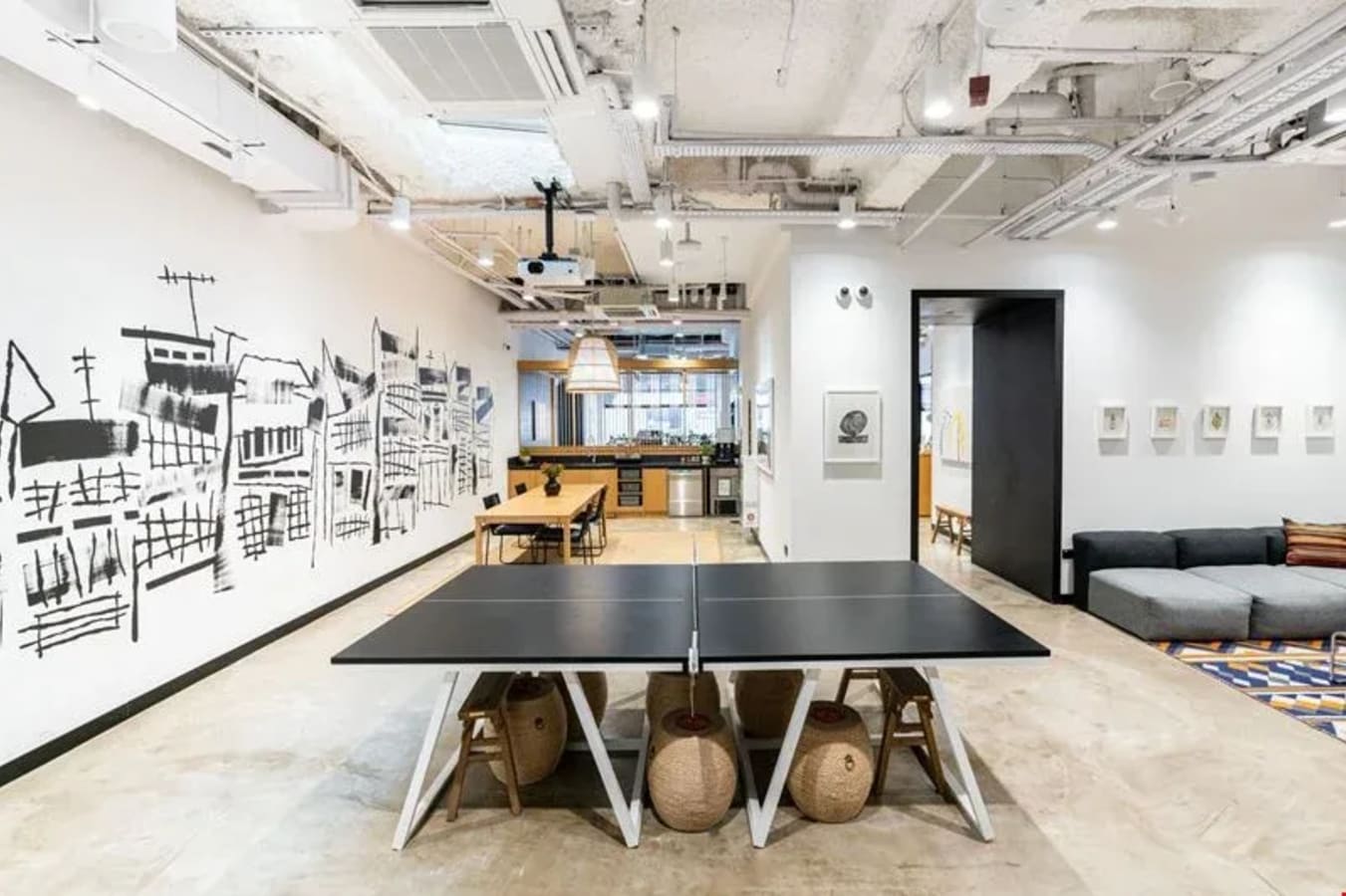 Dynamic coworking space with open layout, creative wall art, and communal amenities in Cross Street.