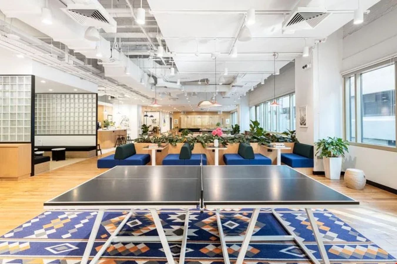 Bright coworking space with modern design, breakout area, and a ping-pong table for relaxation.