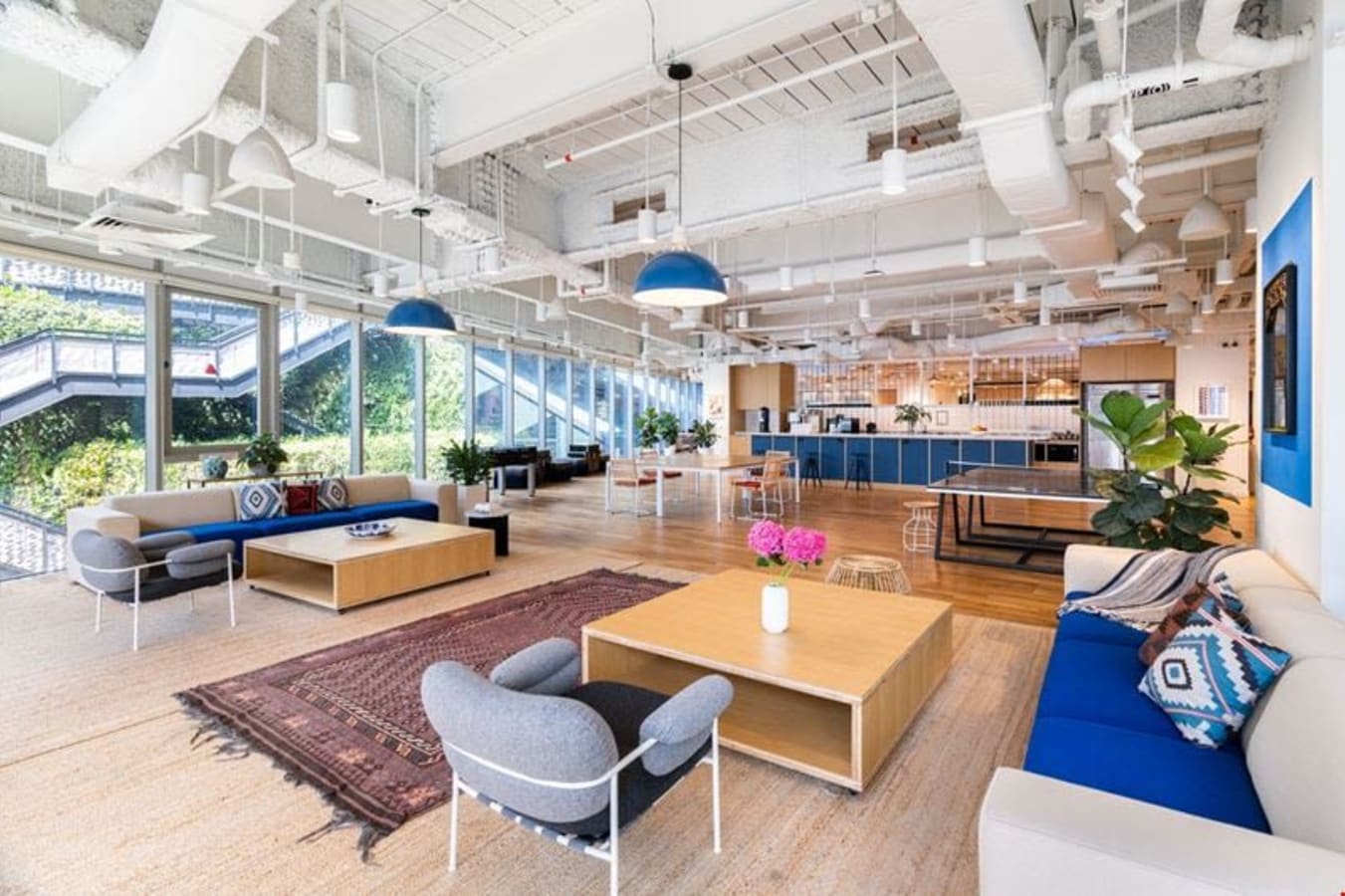 Bright and airy coworking space with modern furniture, large windows, and vibrant decor.