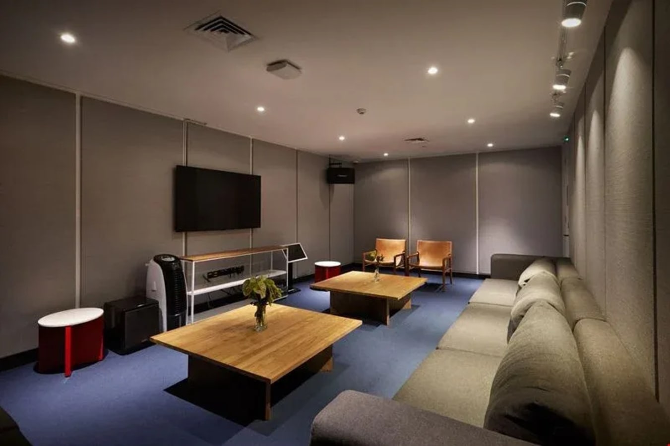 Comfortable breakout area featuring plush seating, flat-screen TV, and modern decor. Ideal for informal meetings.