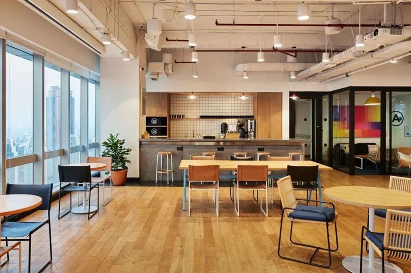 Modern coworking space with natural light, open seating, and a cozy kitchenette in Jakarta.