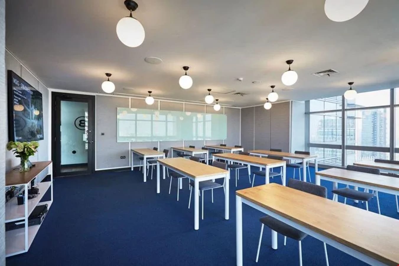 Bright coworking space with modern lighting, large windows, and individual desks in central Jakarta.